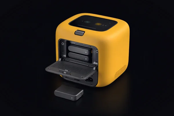 A home hub cube seen from behind with its back panel open, two storage cartridges inside and a third lying in front